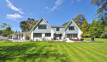 Villa moderna con facciata bianca e giardino curato, casa indipendente immersa nel verde sotto cielo azzurro